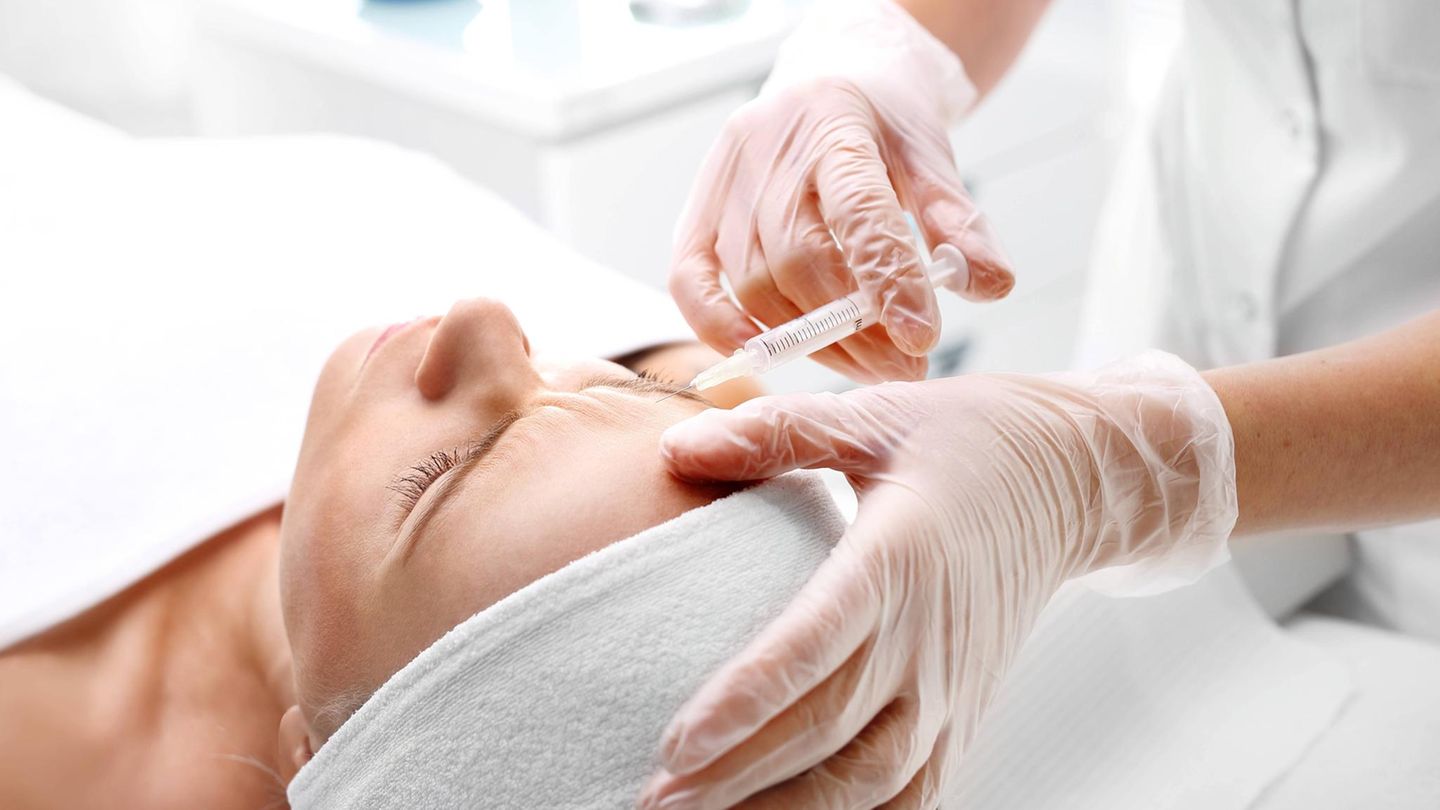 Eine Patientin liegt auf einem Behandlungsstuhl und bekommt Botox in die Stirn injiziert