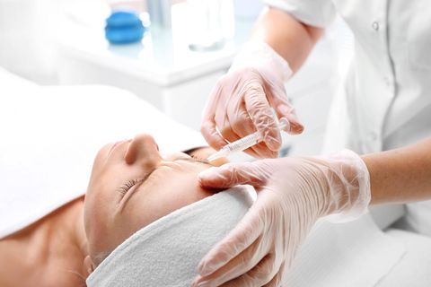 Eine Patientin liegt auf einem Behandlungsstuhl und bekommt Botox in die Stirn injiziert