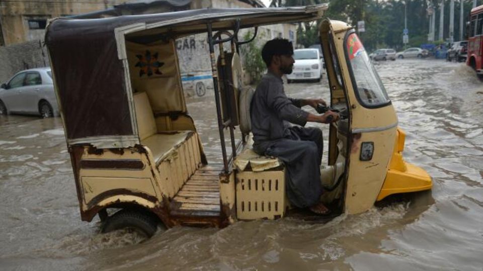 In Pakistan halten die heftigen Regenfälle an. Hier kämpft sich ein Tuk-Tuk-Fahrer über eine überflutete Straße in Karachi.