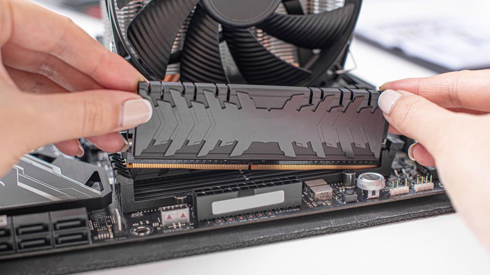 Ein Mann setzt Arbeitsspeicher in einen PC ein.