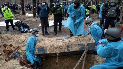 Ukraine, Isjum: Rettungskräfte bewegen einen Sarg während der Exhumierung in dem kürzlich zurückeroberten Gebiet