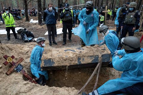 Ukraine, Isjum: Rettungskräfte bewegen einen Sarg während der Exhumierung in dem kürzlich zurückeroberten Gebiet