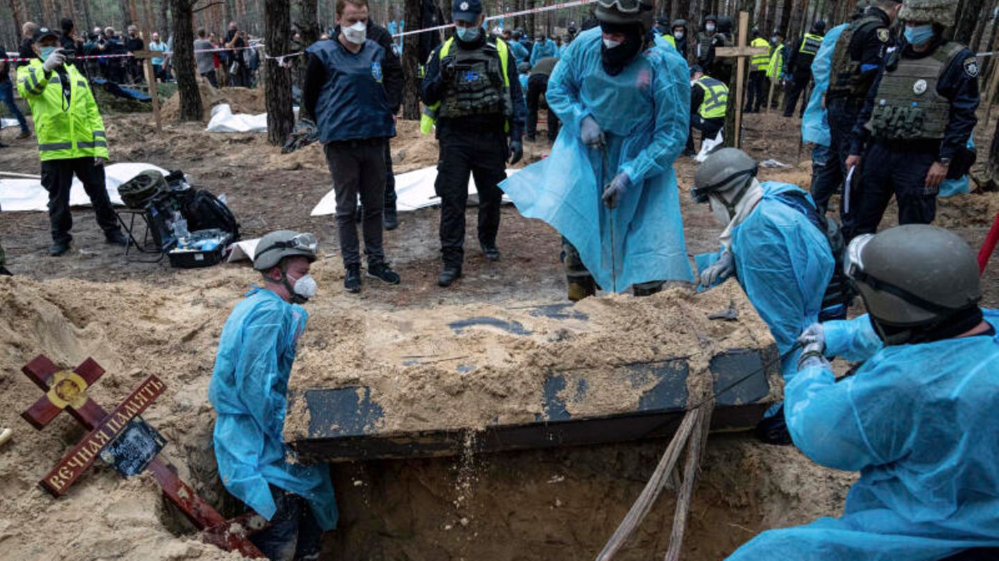 Ukraine, Izyum: Rescue workers move a coffin during exhumation in the recently reclaimed area