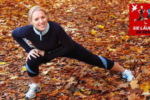 Laufen im Herbst: Eine Läuferin stretcht sich auf verlaubtem Boden
