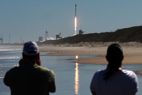 Zwei Männer beobachten vom Canaveral National Seashore aus, wie eine SpaceX Falcon 9 Rakete von der Rampe 39A des Kennedy Space Center startet. Die Rakete trägt 49 Starlink-Internetsatelliten für ein Breitbandnetz.