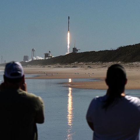 Zwei Männer beobachten vom Canaveral National Seashore aus, wie eine SpaceX Falcon 9 Rakete von der Rampe 39A des Kennedy Space Center startet. Die Rakete trägt 49 Starlink-Internetsatelliten für ein Breitbandnetz.