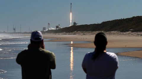 Zwei Männer beobachten vom Canaveral National Seashore aus, wie eine SpaceX Falcon 9 Rakete von der Rampe 39A des Kennedy Space Center startet. Die Rakete trägt 49 Starlink-Internetsatelliten für ein Breitbandnetz.