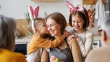 Eine Mutter bemalt mit ihren beiden Kindern Ostereier.