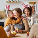 Eine Mutter bemalt mit ihren beiden Kindern Ostereier.