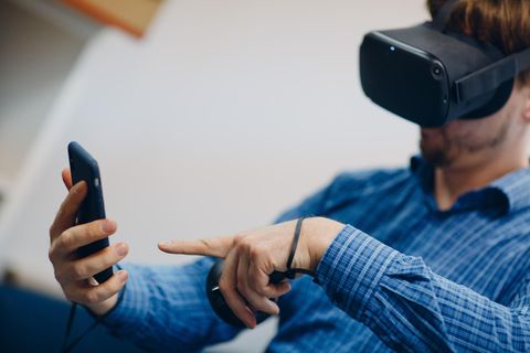 Hologramm-Telefonie: Ein Mann mit einer VR-Brille hält sein Handy in der Hand