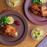 Wiesn-Hendl mit Kartoffelsalat  Das Wiesn Hendl als kulinarischer Oktoberfest-Klassiker gelingt Daheim besonders einfach. Die bayerische Paprika-Marinade aus meinem Familienkochbuch hab ich mit modernem Rauchpaprika verfeinert. So schmeckt der Giggerl aus dem Ofen wie vom Grill. Als Beilage gibt es einen feinen Kartoffelsalat, der von München bis Hamburg wirklich jedem schmeckt.      Zutaten für 2 Personen  Vorbereitungszeit 35 Minuten  Zubereitungszeit 45 Minuten      Wiesn-Hendl:  1 Brathähnchen (ca. 1 kg)  1 gestrichener TL Rauchpaprika  1 gestrichener TL Salz  4 Prisen Pfeffer  4 Prisen Zucker  100 g Butter      Kartoffelsalat:  500 g Kartoffeln  Salz  1 TL Kümmelsamen  200-250 ml Gemüsebrühe  1 EL mittelscharfer Senf  1 Stück rote Zwiebel Salz, Pfeffer  1 gestrichener EL Zucker  3 EL Apfelessig  2 El Sonnenblumenöl  1/2 Bund Petersilie      Dekoration:  1 Stück Zitrone  1/2 Bund Petersilie oder Liebstöckel  2 EL Preiselbeeren      Zubereiten:  Die Kartoffeln waschen und mit der Schale in einem Topf mit Wasser bedeckt auf den Herd stellen.  Kartoffelwasser mit Salz und Kümmelsamen würzen. Die Kartoffeln weich kochen und dann abschütten.  Backofen mit dem Gitter auf mittlerer Schiene ohne Backbleche bei 180°C Heißluft vorheizen.  Das Hähnchen unter fließendem, kalten Wasser abwaschen, trocken tupfen und in einen geeigneten Bräter legen.  Das Hähnchen großzügig mit Rauchpaprika, Salz, Pfeffer und Zucker würzen und unmittelbar in den Ofen schieben.  Den Küchenwecker auf 45 Minuten stellen und die Backofen-Temperatur auf 170°C reduzieren.  Die Kartoffeln schälen, schwarze Augen gründlich entfernen. Eine Schüssel bereit stellen die Kartoffeln abwechselnd in 1-2-3 mm dicke Scheiben in die Schüssel schneiden.  Die Brühe aufkochen, mit Senf verrühren, vom Herd ziehen.  Die Zwiebel halbieren, schälen, in feine Würfel oder in Streifen schneiden und in die heiße, nicht mehr kochende Brühe geben.  Die Zwiebeln 5 Minuten in der Brühe ziehen lassen.   Die Brühe mit Salz, Pfeffer, Zucker und Essig süß säuerlich kräftig abschmecken und über die vorbereiteten Kartoffelscheiben gießen.  Den Kartoffelsalat handwarm abkühlen lassen.  Einige Kartoffeln mit den Händen leicht zerdrücken und so einen gut gebundenen Kartoffelsalat zubereiten.  Kartoffelsalat bis zum Anrichten ziehen lassen.  Wenn der Küchenwecker klingelt den Backofen abschalten und das Hähnchen entnehmen. Den Gargrad prüfen, die Butter zum Hähnchen legen.  Kartoffelsalat mit Salz, Pfeffer, Zucker und Essig final abschmecken und Öl nach Geschmack dazu geben.  Kartoffelsalat in Schälchen anrichten.  Das Hähnchen halbieren und auf warmen Tellern anrichten.  Eine Zitrone halbieren, oder einen Stern ausschneiden, mit Petersilie oder Liebstöckel zum Hähnchen legen.  Preiselbeeren auf dem Teller anrichten und servieren. Den Hähnchen-Bratensaft extra reichen.      Tipp von Koch Thomas Sixt:  Sehr gerne lege ich etwa nach der Hälfte der Garzeit einige Knoblauchzehen und Schalotten zum Hähnchen in den Bräter. Dann ist schon etwas Bratensaft entstanden und die Aromaten können ganz wunderbar im Hähnchensaft garen. Wer es extra knusprig mag, kann das Hähnchen gegen Ende der Garzeit noch kurz grillen.