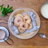 Wiesn-Apfelkiacherl mit falscher Vanille-Sauce  Die Apelkiacherl backen wir in Bayern traditionell im Bierteig. Aufgeblasen und knusprig muss der Teig nach dem Ausbacken sein. Damit es heute schneller geht, gibt es eine falsche Vanillesauce. Schließlich geht Oktoberfest-Küche auch mal schnell.  Zutaten für 4 Personen  Vorbereitungszeit 20 Minuten  Zubereitungszeit 20 Minuten      Falsche Vanille-Sauce:  4 Becher Vanillepudding  1 EL Cointreau      Backteig:  2 kalte Eier Größe M  1 Prise Salz  150 ml Münchner Helles  150 g Mehl  1 TL Puderzucker  1/2 TL Backpulver      Äpfel:  6 Stück Äpfel (Elstar)  300-500 g Rapsöl      Dekoration:  100 g Zucker  1 TL Zimt  1 Bund frische Minze      Zubereiten:  Den Vanillepudding in einer Schüssel mit dem Cointreau verrühren und bis zum Servieren kalt stellen.  Die Eier trennen, die Eiweisse mit einer Prise Salz zu Eischnee schlagen und kalt stellen.  Die Eigelbe leicht anschlagen. Das Bier dazu geben und das Mehl frisch gesiebt mit dem Puderzucker und dem Backpulver einrühren.  Die Äpfel schälen, mit einem Apfelausstecher das Kernhaus entfernen.  Das Rapsöl in einem großen Topf oder in der Fritteuse auf 160-170°C erhitzen.  Den Eischnee zum Bierteig geben und luftig unterheben. Die Teig-Masse soll luftig und gut verbunden sein.  Die Äpfel in 1 cm dicke Scheiben schneiden.  Die Apfelscheiben mit einer langen Pinzette in den Teig tauchen, gut abtropfen lassen, dann im heißen Öl beidseitig knusprig 3-4 Minuten ausbacken.  Die Apfelscheiben aus dem heißen Fett entnehmen und auf einem Küchenkrepp kurz abtropfen lassen.      Anrichten:  Die Apfelringe im Zimtzucker wenden und auf Teller legen.  Mit der Vanille-Sauce servieren und frische Minze dazu reichen.      Tipp von Koch Thomas Sixt:  Der Bierteig lässt sich ebenso mit trockenem Weißwein zubereiten. Der Teig ist auch ausgezeichnet zum Ausbacken von Gemüse geeignet.