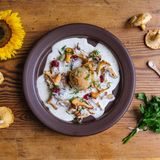 Wiesn-Semmelknödel mit Rahmschwammerl  In Bayern sind wir "narrisch", also verrückt nach Knödeln. Tipp gleich für den Anfang: Sollte die Zeit für das Knödel-Zubereiten nicht reichen, passen dazu auch bayrische Tagliatelle.      Zutaten für 4 Personen  Vorbereitungszeit 20 Minuten  Zubereitungszeit 20 Minuten      Semmelknödel:  300 g Semmeln (Brötchen/Baguette)  1 Stück Schalotte (oder gelbe Zwiebel 37 g)  20 g Butter 150 ml Milch 1/2 TL Salz  6 Prisen Pfeffer schwarz 6 Prisen geriebene Muskatnuss  2 Stück Eier (Größe M – 104 g) 1 EL fein geschnitten Petersilie  Salz für das Kochwasser      Rahmschwammerl:  250 g Pfifferlinge  1 Stück Zwiebel oder zwei Schalotten  1 TL Sonnenblumenöl  300 ml Sahne  1 TL Speisestärke  300 ml Gemüsebrühe  etwas Zitronenabrieb  5 Prisen Salz  5 Prisen Pfeffer  4 Prisen Muskat  2 Prisen Zucker  50 g kalte Butter      Butterbrösel:  80 g Butter  2 EL Semmelbrösel      Dekoration:  4 EL Preiselbeeren  1 TL Petersilie      Zubereiten:  Knödel zubereiten:  Die Semmeln in 0,5 cm große Würfel schneiden und in einer Schüssel bereit stellen.  Die Schalotte halbieren, schälen, in feinste Würfel schneiden und mit 20 g Butter farblos 5 Minuten glasig schwitzen.  Die Zwiebelwürfel mit der Milch aufgießen und aufkochen. Die Milch mit Salz, Pfeffer und Muskat abschmecken und über die Semmelwürfel gießen.  Die Semmelmasse vorsichtig verrühren und lauwarm abkühlen lassen.  Die Eier aufschlagen und zur Semmelmasse geben, fein geschnittene Petersilie dazu geben und vermischen.  Einen Topf mit Wasser aufstellen und bei Unsicherheiten einen Probekloss zubereiten. 50 g Knödelmasse formen und in das kochende Salzwasser einlegen. Den Knödel schwach wallend 12-14 Minuten ziehen lassen. Dann die Konsistenz überprüfen. Optional können Sie die Knödelmasse mit wenig Semmelbrösel fester gestalten.  Die Knödelmasse mit dem Eisportionierer portionieren und mit befeuchteten Händen runde Knödel drehen. Die Knödel zum Kochen bereit stellen.  Die Teller bei 80°C im Backofen warm stellen.      Rahmschwammerl zubereiten:  Die Pfifferlinge bei leichter Verschmutzung mit Pinsel und kleinem Messer putzen. Alternativ bei starker Verschmutzung: Vier Liter kaltes Wasser mit 2 EL Essig und 2 EL Mehl verrühren. Die Pilze flink im Mehlwasser waschen, kurz unter fließendem kalten Wasser abspülen und in der Salatschleuder trocken schleudern.  Die Pilze halbieren oder je nach Größe mundgerecht adrett vorbereiten und in einem Topf bei hoher Hitze mit dem Sonnenblumenöl anbraten.  Die Zwiebel oder Schalotten halbieren, schälen und in feine Würfel schneiden.  Etwa 4 EL Pilze für die Dekoration entnehmen und auf einem Teller bereit stellen.  Zwiebel zu den Pilzen in den Topf geben und 2 Minuten bei reduzierter Hitze anschwitzen.  Die Pilze im Topf mit der Gemüsebrühe ablöschen und aufkochen.  Die Knödel in das kochende Wasser einlegen und schwach wallend 12-14 Minuten ziehen lassen.  Die Speisestärke in die kalte Sahne geben und verrühren oder in einem Becher schütteln.  Die vorbereitete Sahne langsam zu den Pilzen gießen, die Soße dabei aufkochen.  Die Schwammerl-Sauce mit etwas Zitronenabrieb, Salz, Pfeffer, Muskat und Zucker abschmecken.    Butter in einem Topf schmelzen, die Butterbrösel zugeben und leicht Farbe nehmen lassen. Herdplatte ausschalten und mit Salz würzen.      Anrichten:  Mit einer Schaumkelle die gesamte Schwammerl und Zwiebeln auf heiße Teller anrichten.  Knödel aus dem Wasser heben und auf Küchenkrepp abtropfen lassen.  Knödel zu den Schwammerln setzen.  Die verbliebene Soße mit kalter Butter schaumig aufmixen und auf den Tellern anrichten.  Beiseite gestellte Pilze als Dekoration schön dazu richten.  Die Preiselbeeren im Pilzschaum anrichten.  Die Butterbrösel über die Knödel gießen und mit frisch geschnittener Petersilie vollendet servierenn      Tipp von Koch Thomas Sixt:  Das Waschen der Schwammerl ist fast so umstritten wie Öl im Kochwasser für Nudeln. Ich halte es praktisch und pragmatisch: Sind die Schwammerl zu schmutzig oder soll es schnell gehen, dürfen diese bei mir einen flinken Freischwimmer machen. Wer das schnell macht, wird keinen merklichen Geschmacksverlust bemerken. Warum kommt Mehl und Essig (Säure) ins Wasser? Die Säure verändert den PH-Wert vom Wasser und das Mehl bindet den Schmutz. Ein Pilzgericht ohne Zähneknirschen ist so garantiert. Beim Knödel-Essen daran denken: Knödel schneidet man nicht sondernd zupft diese am Teller. Nur flaumige Knödelstückerl können die Soße gut aufnehmen.