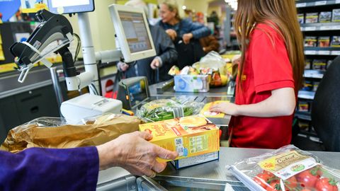 Eine Kundin nimmt an einer Supermarktkasse ihre Einkäufe vom Kassenband