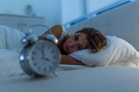 Frau liegt nachts wach und kann nicht schlafen