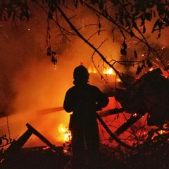 Ein Feuerwehrmann vor einem brennenden Haus