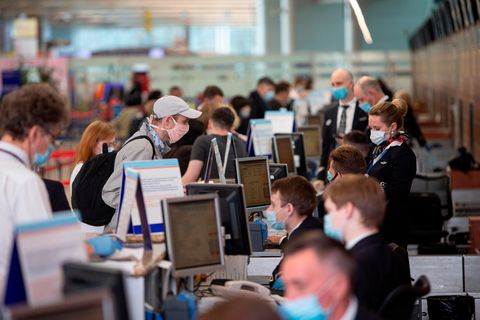 Ein Passagier mit Gesichtsmaske steht vor einem Abfertigungsschalter am Internationalen Flughafen Scheremetjewo in Moskau