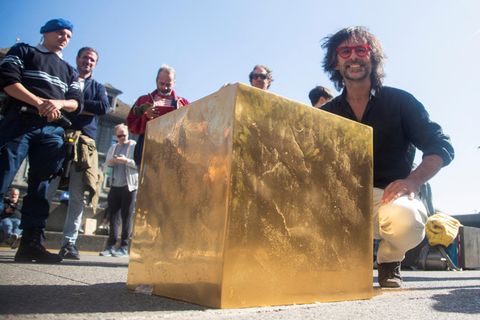 Künstler Niclas Castello kniet hinter seinem Werk "The Castello Cube" in Zürich 