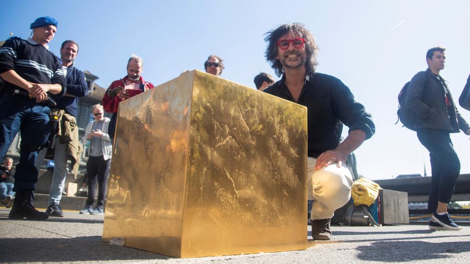 Artist Niclas Castello kneels behind his work "The Castello Cube" in Zurich 