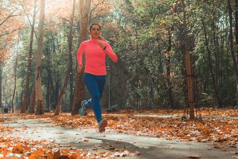 Jogging Outfit im Herbst: Junge Läuferin in einem Park