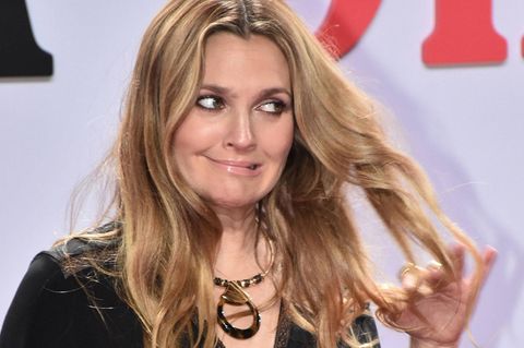 Drew Barrymore steht vor einer Werbewand