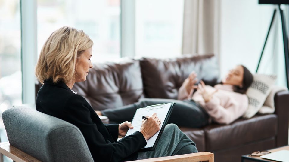 Eine Frau liegt auf der Couch bei einer Psychotherapeutin.