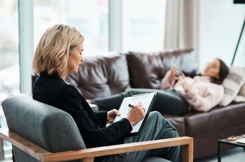 Eine Frau liegt auf der Couch bei einer Psychotherapeutin.