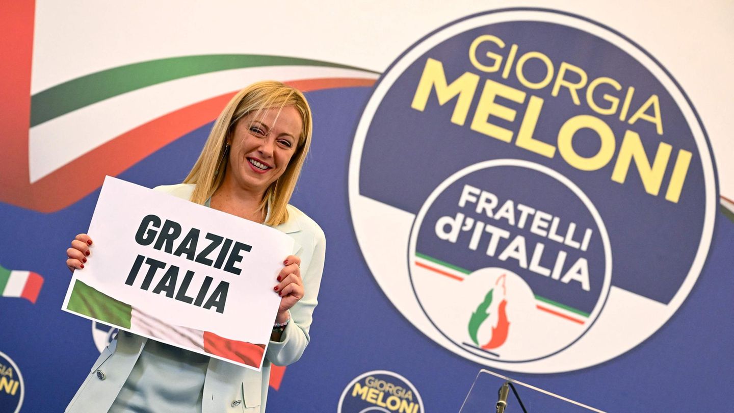 Giorgia Melonie hält ein Schild "Grazie Italia" hoch