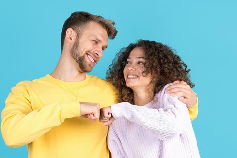 Ein Mann und eine Frau lachen sich an und halten ihre geballten Fäuste aneinander.