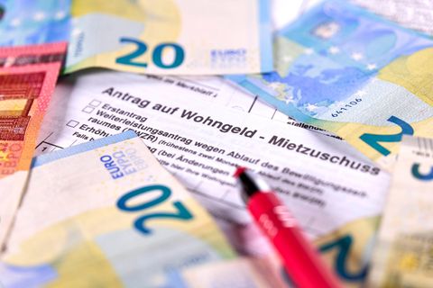 Ein Antrag auf Wohngeld liegt unter Geldscheinen und einem Stift