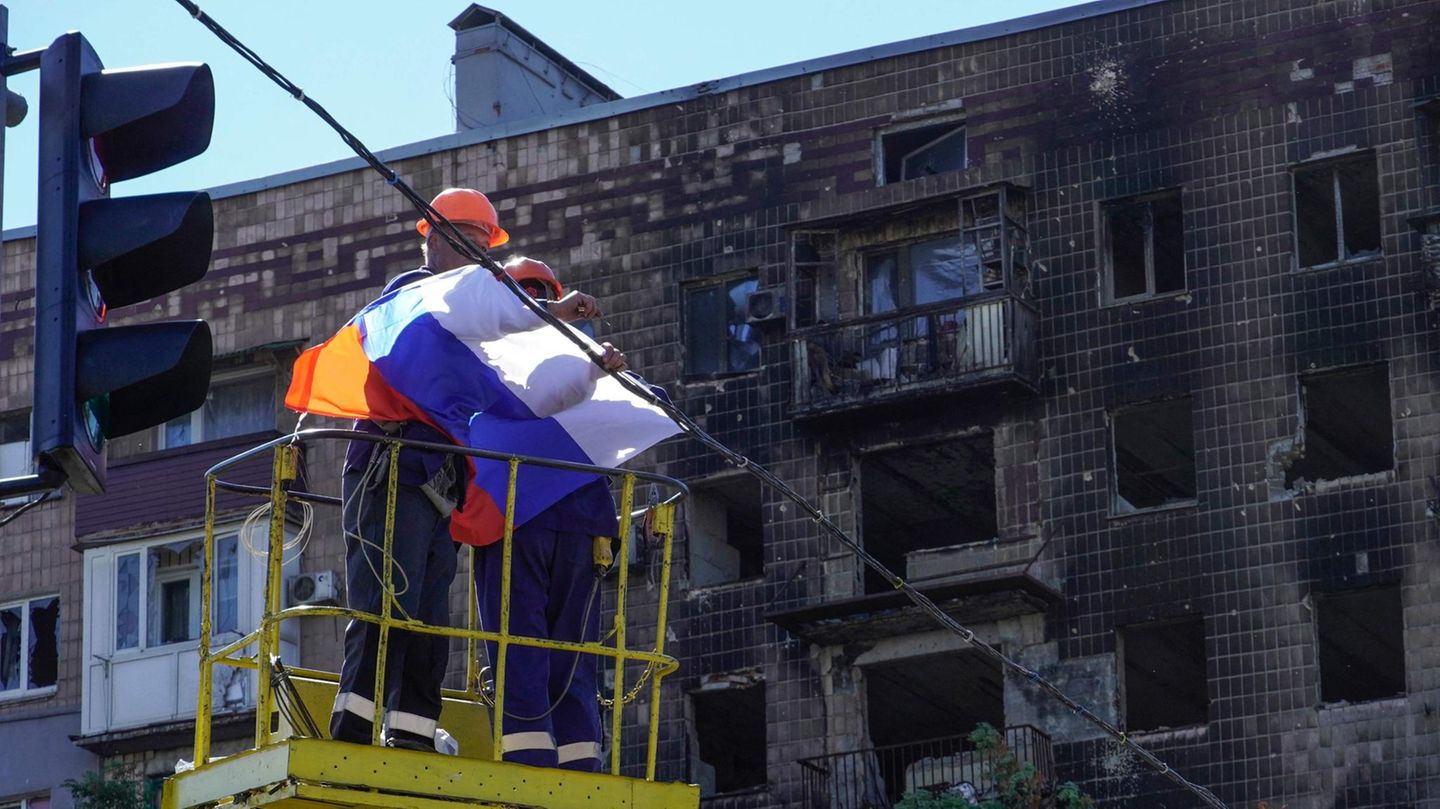 Arbeiter befestigen eine russische Flagge über einer Straße in Mariupol