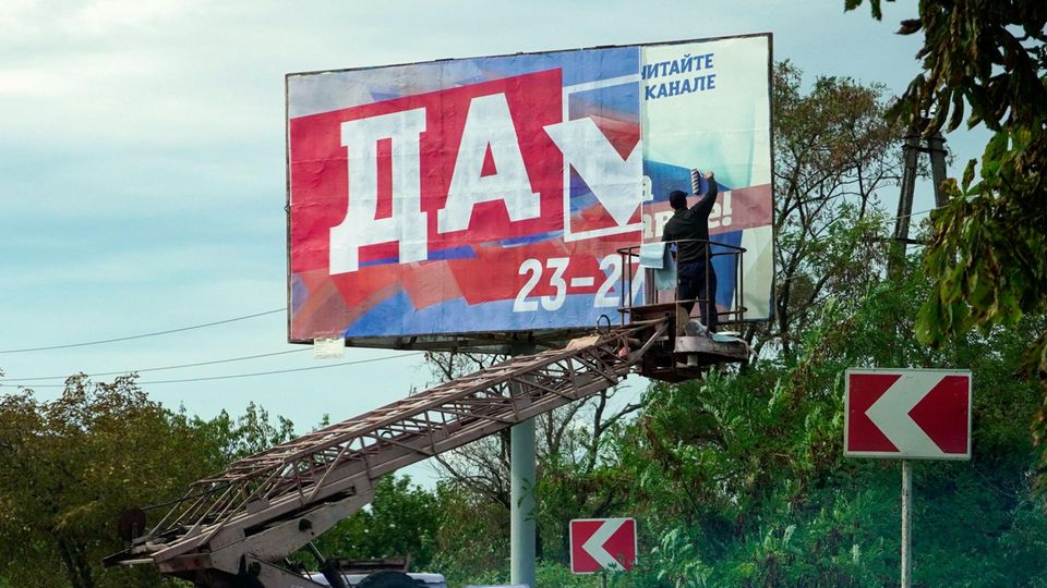 Ein Mann klebt in Berdyansk ein Plakat, das für das Referendum wirbt. Russlands Staatsmedien zeigen nur begeisterte Bürger, die sich auch wegen der sozialen Sicherheiten – Kremlchef Wladimir Putin verspricht etwa höhere Renten – auf die Aufnahme in die Russische Föderation freuen. 