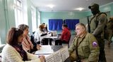 Der von Russland eingesetzte Bürgermeister von Mariupol, Kostjantyn Iwaschtschenko, spricht mit Wahlhelferinnen in einem Wahllokal – nicht ohne schwer bewaffneten Personenschützer im Rücken 