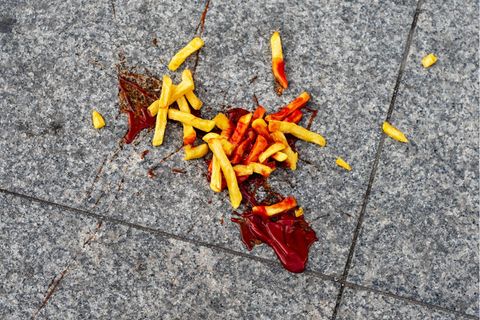 A portion of French fries with ketchup fell on the street