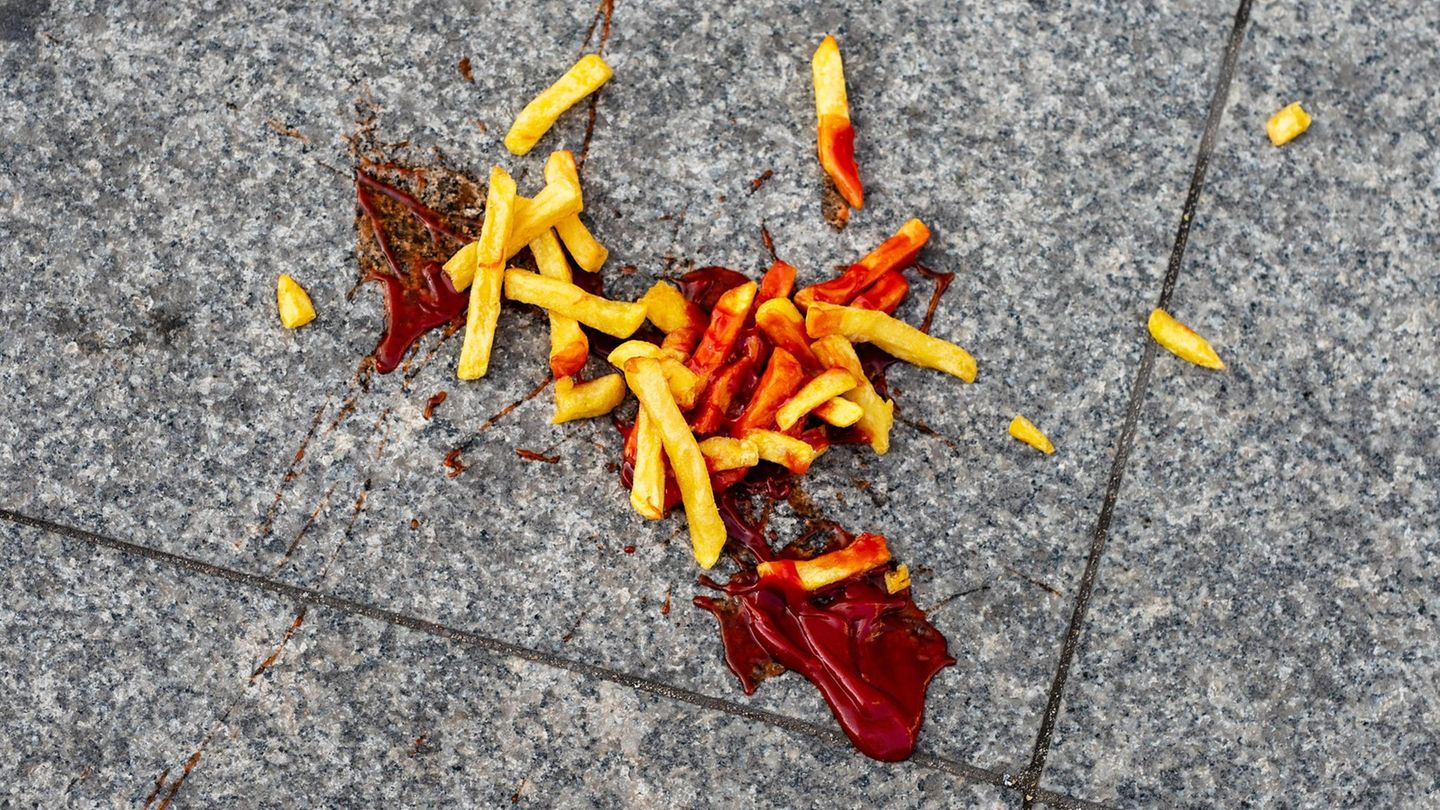 A portion of French fries with ketchup fell on the street