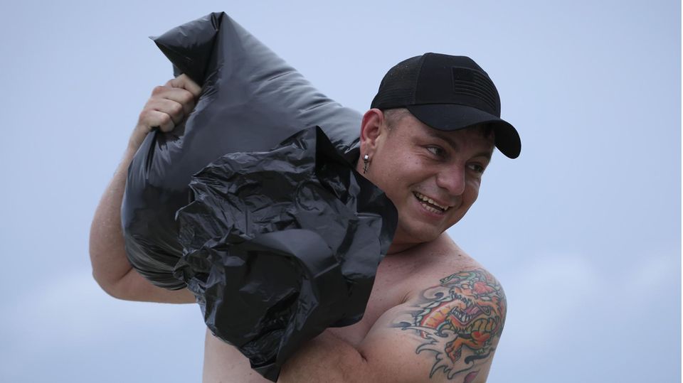 Andere, wie Erwin Martinez am Strand bei Tampa, schleppen da schon Sandsäcke