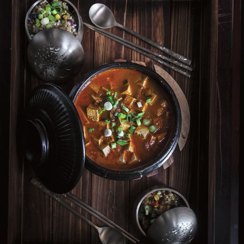 Scharfer Doenjang Chigae (Eintopf mit fermentierter Sojabohnenpaste)      Zutaten:  1 EL Sesamöl  1 EL Gochugaru (Chiliflocken)  1⁄4 Zwiebel, fein gewürfelt  3 Knoblauchzehen, fein gehackt  1 kleine Kartoffel, geschält und gewürfelt  80 g Zucchini, gewürfelt  Salz  1⁄2 TL schwarzer Pfeffer aus der Mühle  3 EL Doenjang (Sojabohnenpaste)  1 EL helle Sojasauce  500 ml Gemüsebrühe  500 g mittelfester oder fester Tofu, in mundgerechte Würfel geschnitten  2 Frühlingszwiebeln, gehackt  1 Jalapeño, geputzt und in dünne Streifen geschnitten      Zubereitung:  1. Das Sesamöl bei mittlerer Hitze in einem mittelgroßen Ddukbaegi oder Schmortopf erhitzen. Sofort das Gochugaru hinzufügen und mit einem Kochlöffel zu rühren beginnen. Darauf achten, dass das Gochu- garu nicht verbrennt (dunkel wird), da es sonst bitter schmeckt.  2. Sobald das Gochugaru zu blubbern und schäumen beginnt, Zwie- beln, Knoblauch, Kartoffeln, Zucchini, 1 TL Salz und Pfeffer hinzufügen. Alles etwa 1 Minute garen, bis die Zutaten ihr Aroma entfalten.  3. Doenjang hinzufügen und rühren, bis das Gemüse gleichmäßig damit überzogen ist. Dann das Ganze mit Sojasauce ablöschen und die Gemüsebrühe angießen. Den Tofu hinzufügen und den Eintopf zum Kochen bringen. Dann die Hitze reduzieren und den Eintopf etwa 20 Minuten köcheln lassen, bis die Kartoffeln schön zart sind.  4. Schließlich die Frühlingszwiebeln und die Jalapeño hinzufügen und vor dem Servieren weitere 2 Minuten garen
