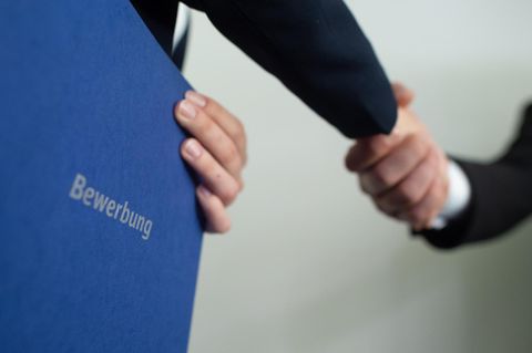 Krise: Ein Personaler und eine Bewerberin geben sich die Hand, die Bewerberin hält eine Bewerbungsmappe in der Hand