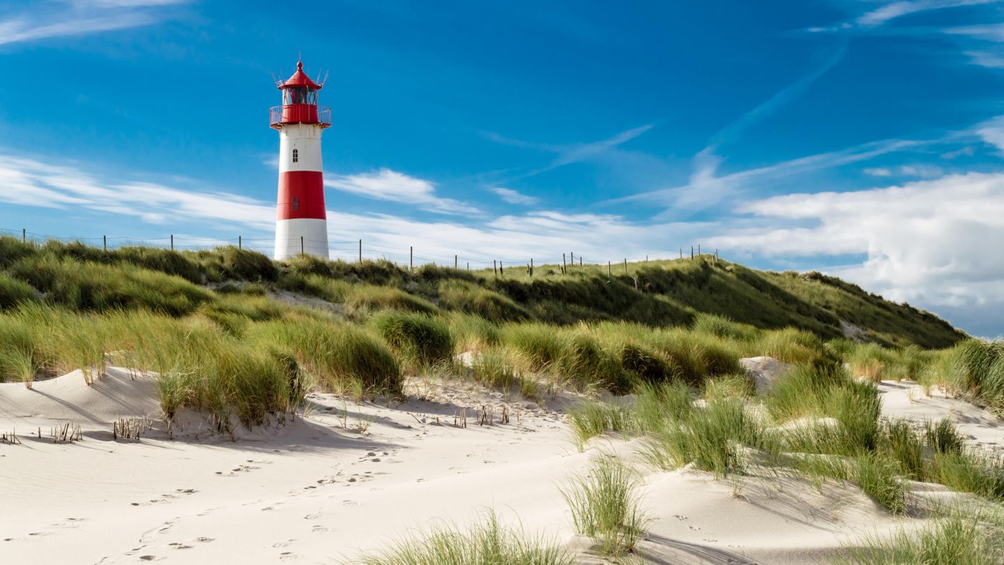 Ein Leuchtturm in einer Dünenlandschaft.