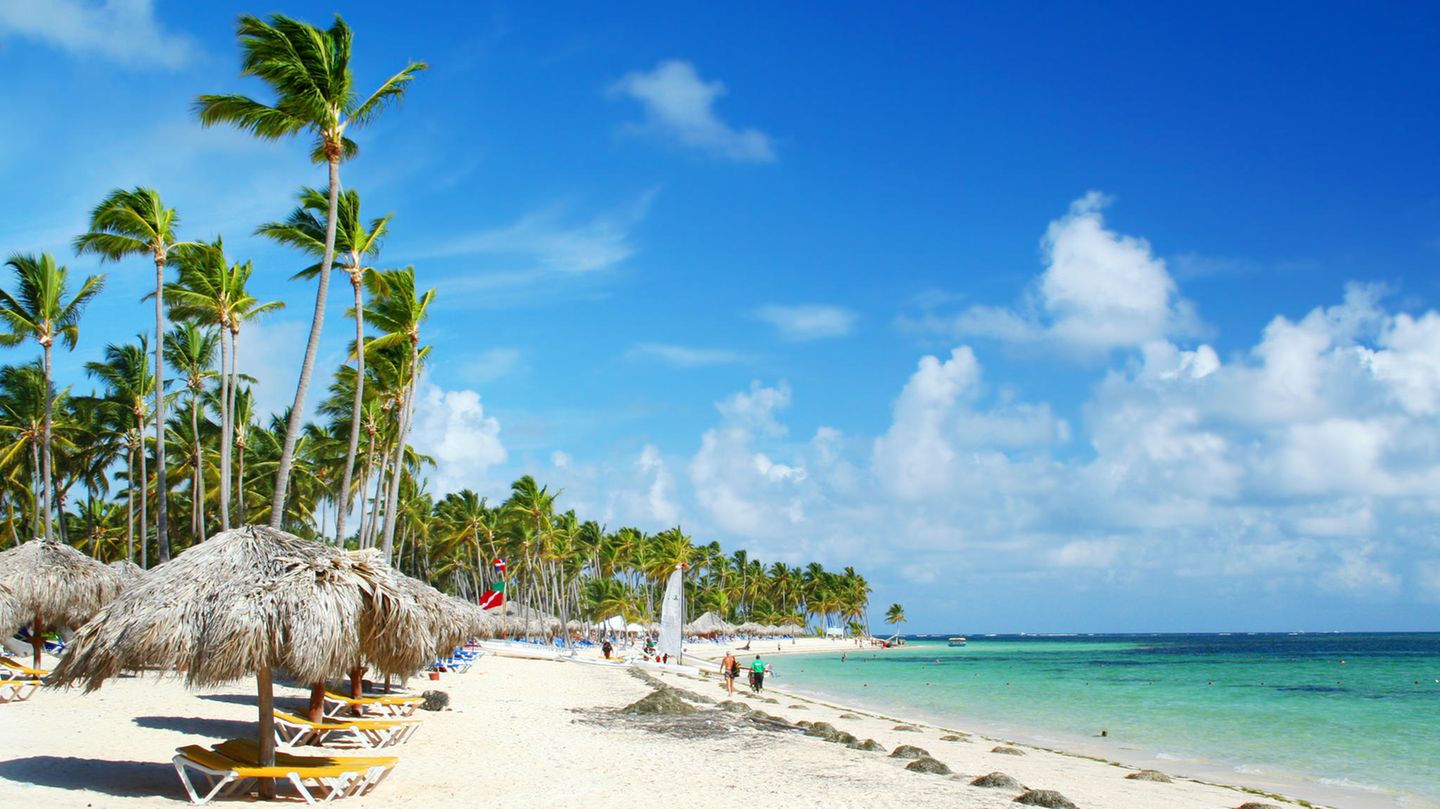 Ein Strand mit türkisblauem Wasser und Sonnenliegen.