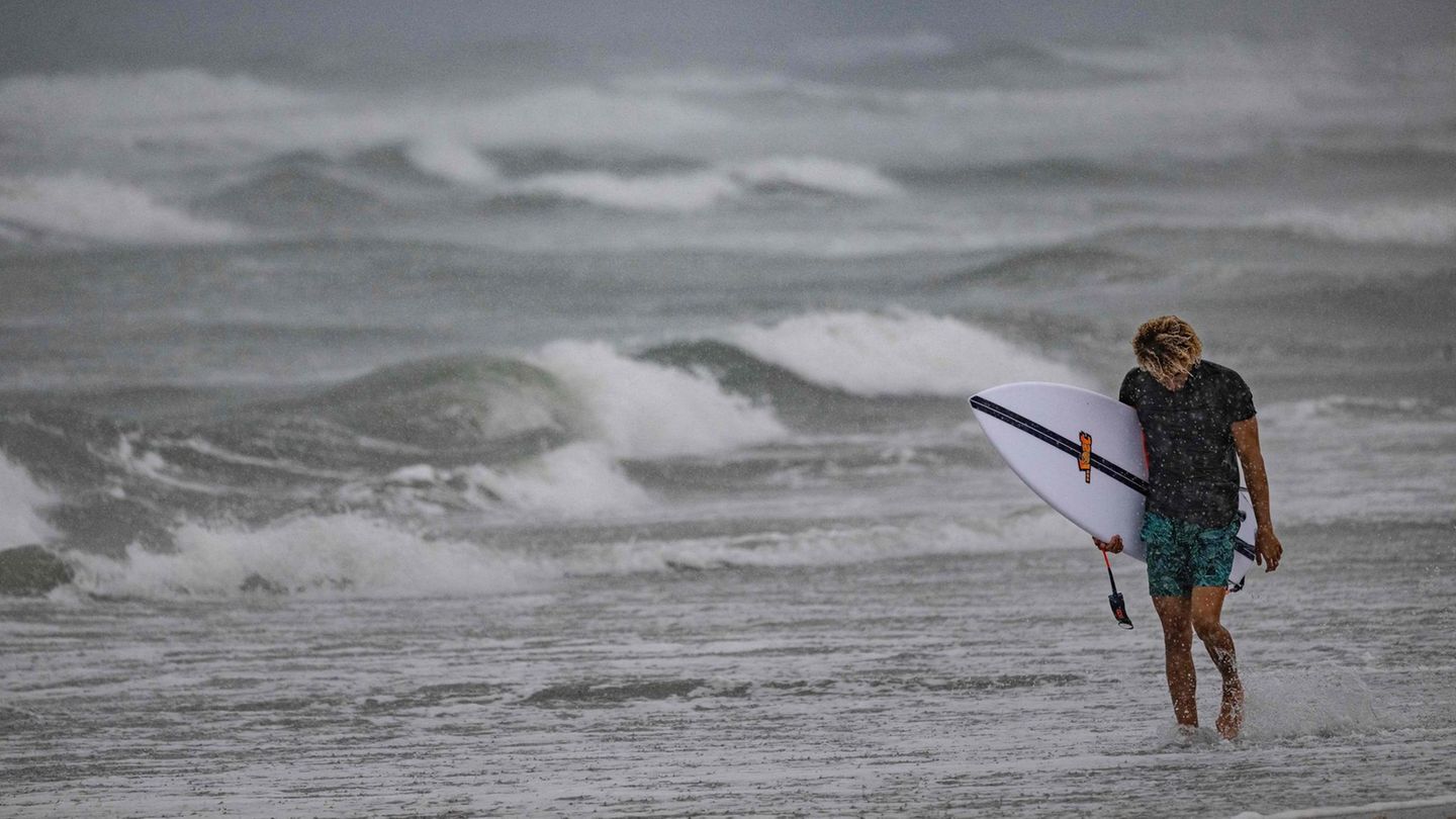 Unverdrossen geht dieser Surfer am Strand von Cocoa Beach entlang. Hurrikan "Ian" bringt natürlich auch ungewöhnlich starke Wellen mir sich