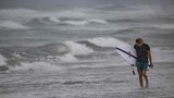 Unverdrossen geht dieser Surfer am Strand von Cocoa Beach entlang. Hurrikan "Ian" bringt natürlich auch ungewöhnlich starke Wellen mir sich