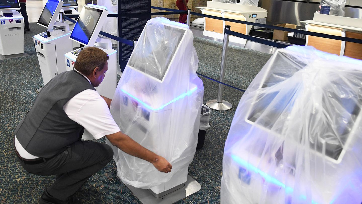Delta-Airlines-Mitarbeiter Juan Martinez deckt einen Check-in-Terminal am Orlando International Airport mit einer schützenden Plastiktüte ab, denn der Flughafen schließt wegen "Ian"