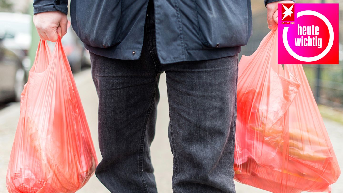 Ein Mann trägt seine Einkäufe in Plastiktüten nach Hause
