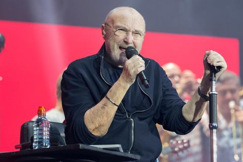 Phil Collins mit Mikrofon in der Hand bei einem Auftritt auf der Bühne