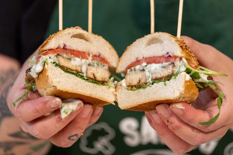 Eine Köchin hält auf der Messe Biofach während einer Koch-Show zu veganem Fischersatz Burger in den Händen
