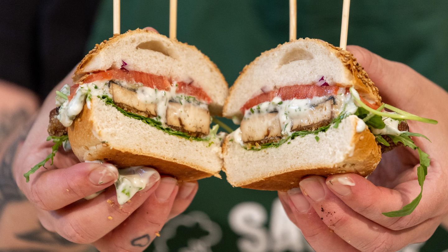 Eine Köchin hält auf der Messe Biofach während einer Koch-Show zu veganem Fischersatz Burger in den Händen