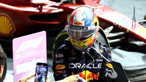 Ein Mann in Rennanzug und Helm steigt umringt von Fotografen aus einem Formel 1 Boliden