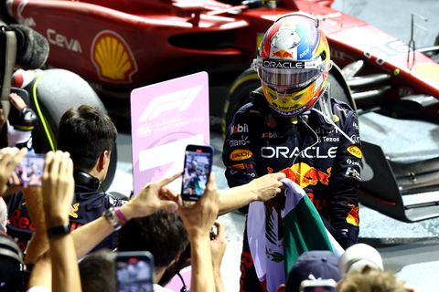 Ein Mann in Rennanzug und Helm steigt umringt von Fotografen aus einem Formel 1 Boliden