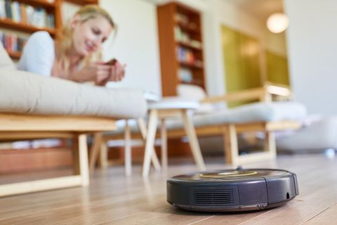 Eine Frau liegt auf dem Sofa, ein Saugroboter fährt vorbei. Ein IT-Experte ist besorgt.